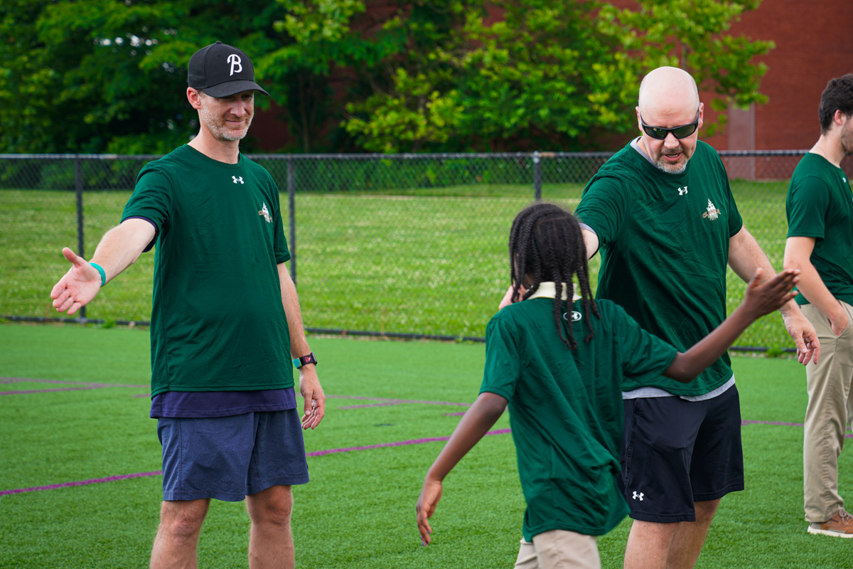 Geoff Lindsay, Business Development, and Eric Mauldin, State and Local Tax, shake hands with youth during a field day at Cal Ripken Sr Foundation.