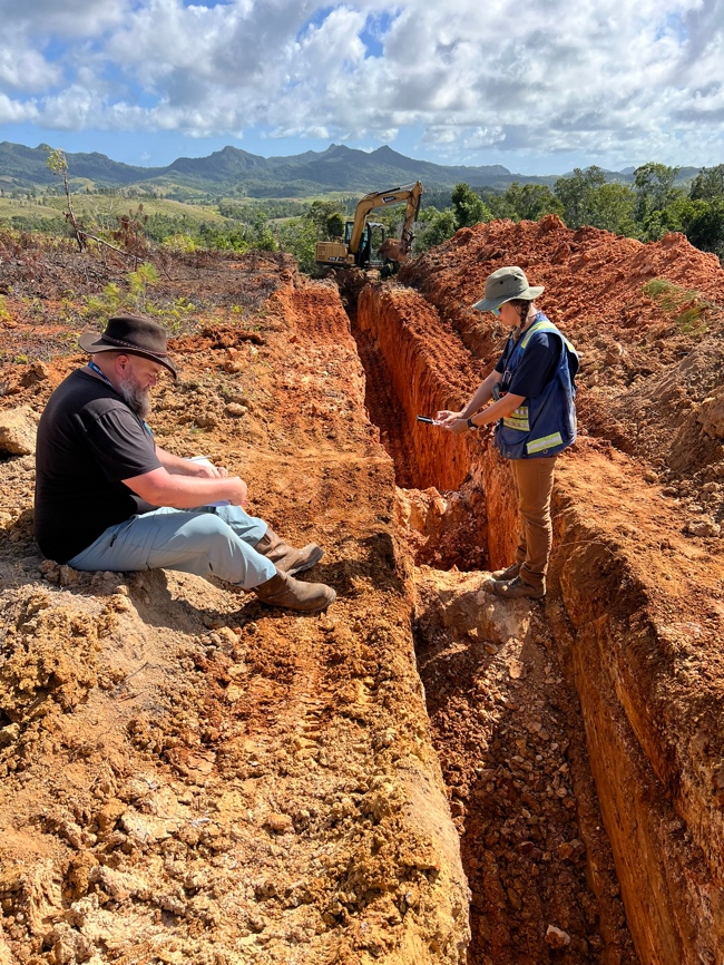 A person and person sitting on a dirt pit

Description automatically generated