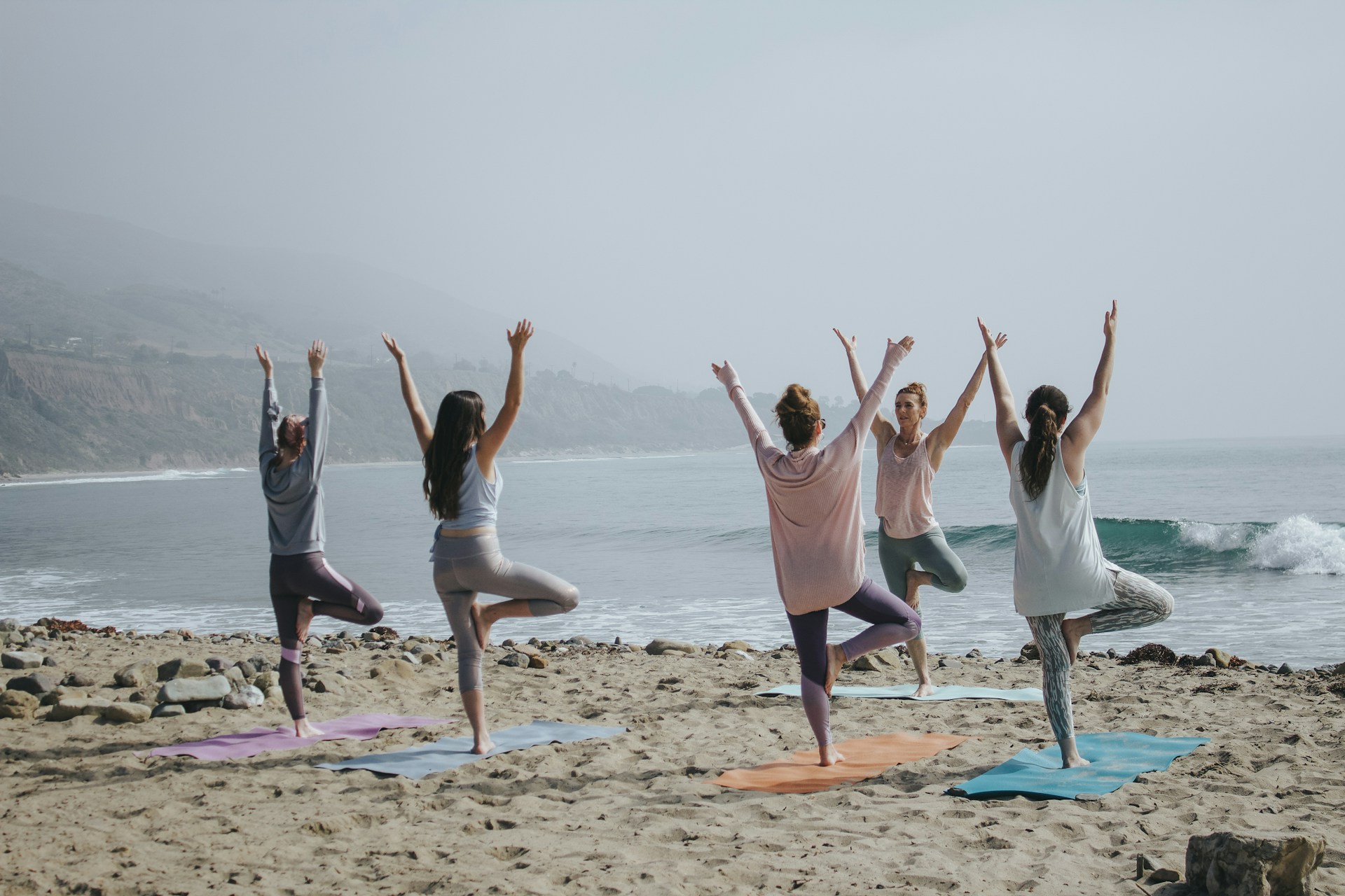 A group of women practices yoga on a beach, reflecting a serene, health-conscious lifestyle. This image embodies Sisel Health's commitment to holistic wellness, toxic-free health supplements, natural wellness supplements, organic skin care solutions, and chemical-free personal care, promoting both physical and mental well-being in a natural setting.